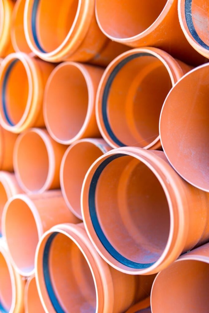 stack of orange PVC pipes ready for a sewer line replacement project