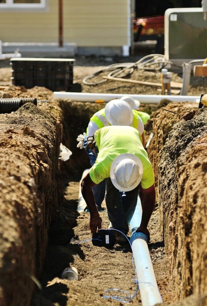 construction crew in a trench performing a professional water line repair and replacement for a residential property